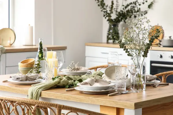 Güzel çiçekleri, okaliptüs dalları ve aydınlık mutfakta mumları olan zarif bir masa. Yakın plan.