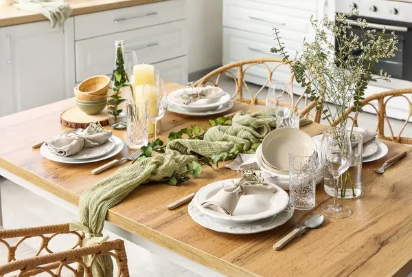 Güzel çiçekleri, okaliptüs dalları ve aydınlık mutfakta mumları olan zarif bir masa. Yakın plan.