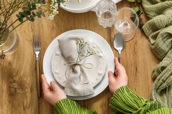 Katlanmış peçeteyle güzel çiçekleri servis masasının üstüne koyan genç bir kadın.