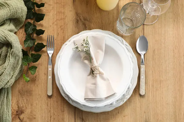 Restoranda sunulan ahşap masa üzerinde katlanmış peçete ve güzel çiçeklerle dolu bir tabak.