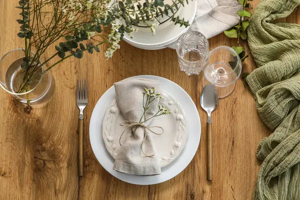 Restoranda sunulan ahşap masa üzerinde katlanmış peçete ve güzel çiçeklerle dolu bir tabak.