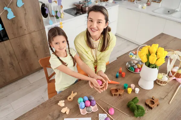 Mutlu anne ve küçük tatlı kızı neşeli mutfakta boyanmış Paskalya yumurtaları, üst manzara