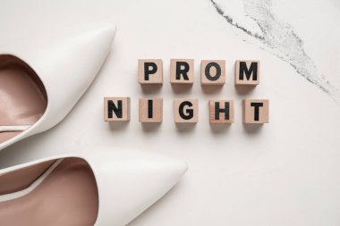 Balo gecesi yazılı küpler ve beyaz mermer arka planda yüksek topuklu ayakkabılar.