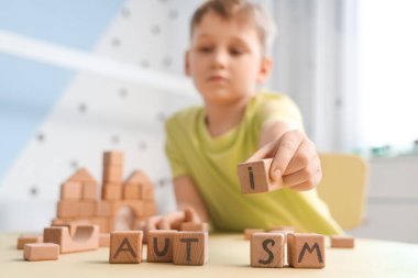Evdeki masada AUTISM sözcüğüyle küçük çocuk ve küpleri, yakın plan.
