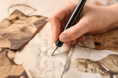 Mektup yazan bir kadının eli ve akrabalarının eski fotoğrafları. Aile ağacı kavramı