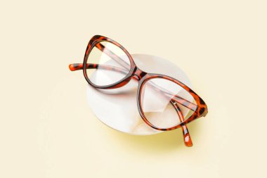 Soluk sarı arkaplanda şık leopar desenli gözlüklerle dur.