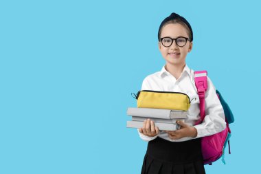 Sırt çantası, kalem kutusu ve mavi arka plan kitapları olan küçük bir kız öğrenci.