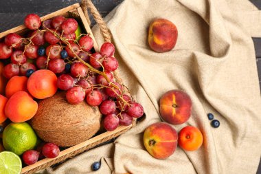 Masanın üzerinde farklı taze meyveler olan tahta kutu.