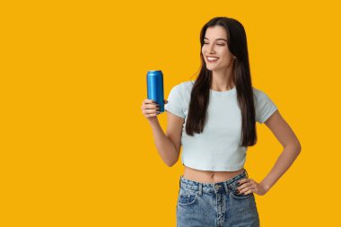 Sarı arka planda soğuk bira kutusuyla güzel genç bir kadın.