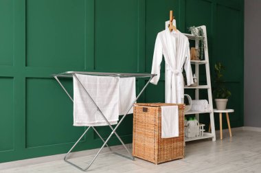 Çamaşır sepeti, kurutma makinesi ve raf ünitesi olan odanın içi.