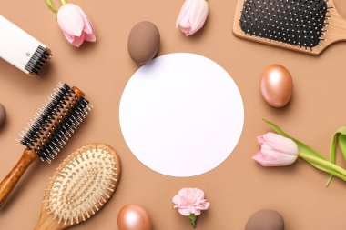 Açık kahverengi arka planda kuaför aksesuarları, laleler ve Paskalya yumurtaları olan boş bir kart.