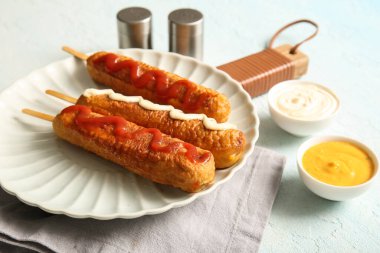 Lezzetli mısırlı sosis ve açık mavi arka planda bir kase sos.