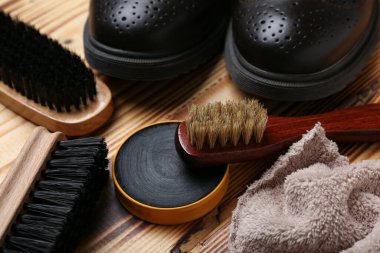 Ahşap arka planda fırçalar, parlak ayakkabılar, kumaş ve ayakkabı cilası.