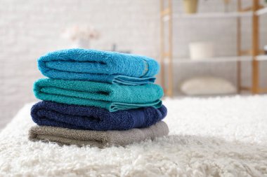 Beyaz yatakta temiz yumuşak havlular yığını, yakın plan.