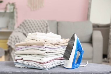 Mavi ütü ve giysi yığını bulanık arkaplanda.