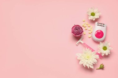 Pembe arka planda çiçek, jilet ve balmumu olan modern epilatör.