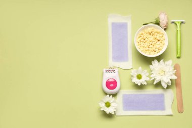 Tıraş bıçağı, balmumu şeritleri ve yeşil arka planda çiçekleri olan modern epilatör.