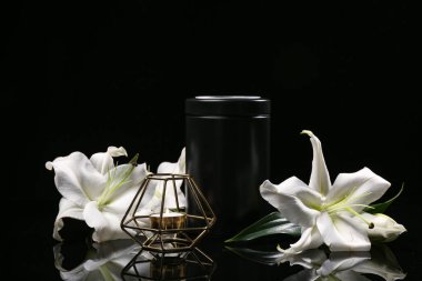 Beyaz çiçekler, morg vazosu ve siyah arka planda şamdan.