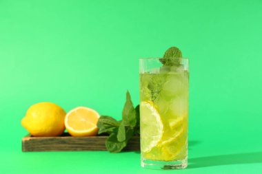 Limonlu ahşap tepsi, nane ve yeşil arka planda bir bardak lezzetli limonata.