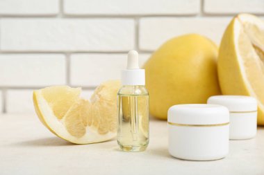 Şişeyle, kozmetik ürünlerle ve beyaz tuğla duvarın yanında taze çiçeklerle güzel bir kompozisyon.