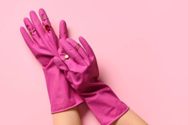 Lastik eldivenli kadın eller ve pembe arka planda güzel yüzükler.