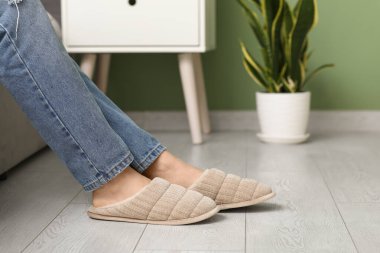 Şık terliklerle kadın bacakları odada yerde.