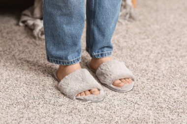 Oturma odasında terlik giymiş kadın bacakları.