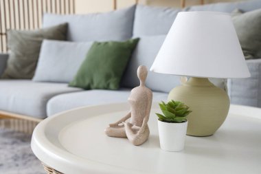 Oturma odasındaki masada üzerinde çiçek ve biblo olan lamba, yakın plan.