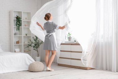 Otel odasının penceresinin yanındaki genç oda hizmetçisi.