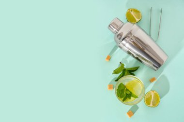 Bir bardak taze mojito. Kokteyl karıştırıcı ve mavi arka planda şeker.