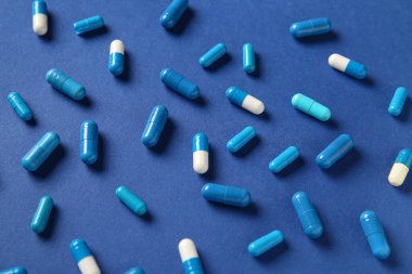 Mavi arka planda farklı haplar, yakın plan.