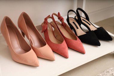 Odadaki ışık duvarının yanındaki rafta şık kadın ayakkabıları, yakın plan.