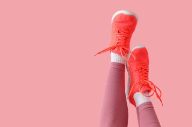 Pembe arka planda spor ayakkabılı kadın bacakları