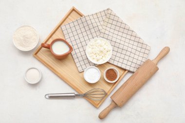 Beyaz arka planda tatlı tarçınlı rulo hazırlamak için farklı malzemeler içeren ahşap tahta tahta.