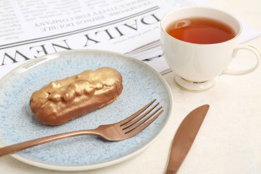 Tatlı ekinli tabak, arka planda çay ve gazete.