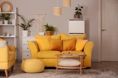 Sarı kanepe, çekmeceler ve yeşil bitkilerle oturma odasının içinde.