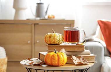 Balkabaklı, kitaplı ve sonbahar yapraklı bir bardak sıcak çay.