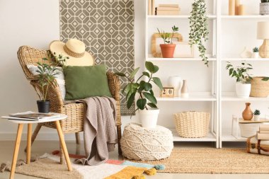 Beyaz duvarın yanında koltuk, ev bitkileri ve raf üniteleri olan modern bir oda.