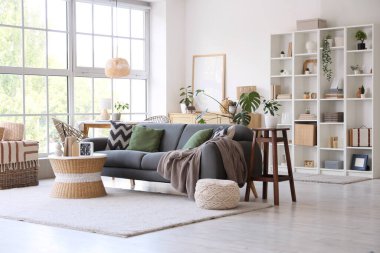 Gri kanepesi, sehpası ve raf ünitesi olan modern oturma odasının içinde.