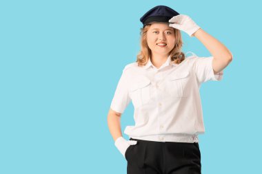 Mavi arka planda genç bayan pilot selamlıyor. Erkek mesleği kavramındaki kadın.