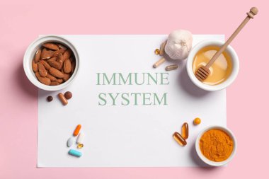 Kağıt levha içinde IMMUNE SİSTEM, farklı sağlıklı yiyecekler ve pembe arka planda haplar