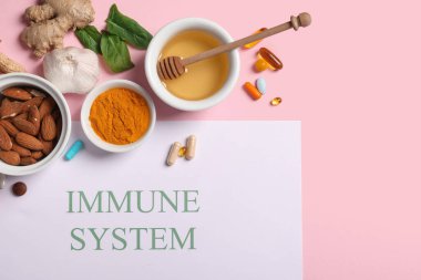Kağıt levha içinde IMMUNE SİSTEM, farklı sağlıklı yiyecekler ve pembe arka planda haplar
