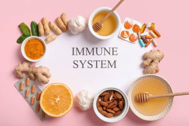 Kağıt levhada IMMUNE Sistemleri, haplar ve pembe arka planda farklı sağlıklı yiyecekler var.