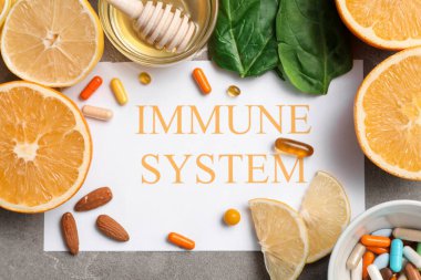 Kağıt sayfası IMMUNE SİSTEM, narenciye meyveleri, ıspanak, bal ve grunge arkaplanda haplar, yakın plan