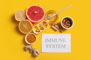 IMMUNE Sistemine ait metin kompozisyonu, sarı arka planda sağlıklı yiyecek ve haplar