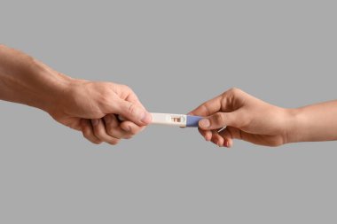 Gri arka planda hamilelik testi yapan çift