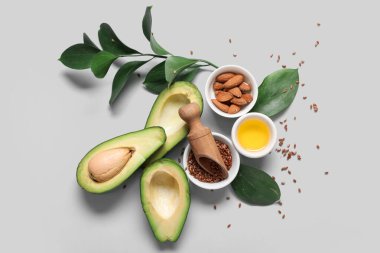 Olgun avokado, yağlı kase, badem ve gri arka planda keten tohumu karışımı.