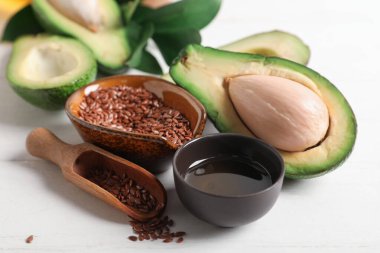 Olgun avokado, yağlı kase ve keten tohumları açık ahşap masada.