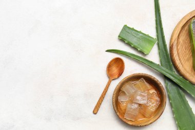 Taze aloe vera yapraklı ahşap kase ve beyaz grunge arka planda kaşık.