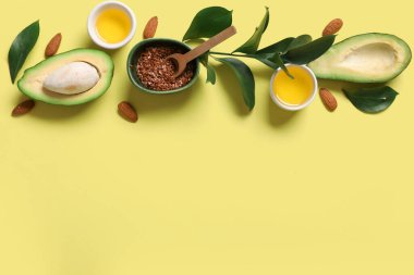 Taze avokado, yağlı kase, keten tohumu ve renk arka planında bitki dalı olan kompozisyon